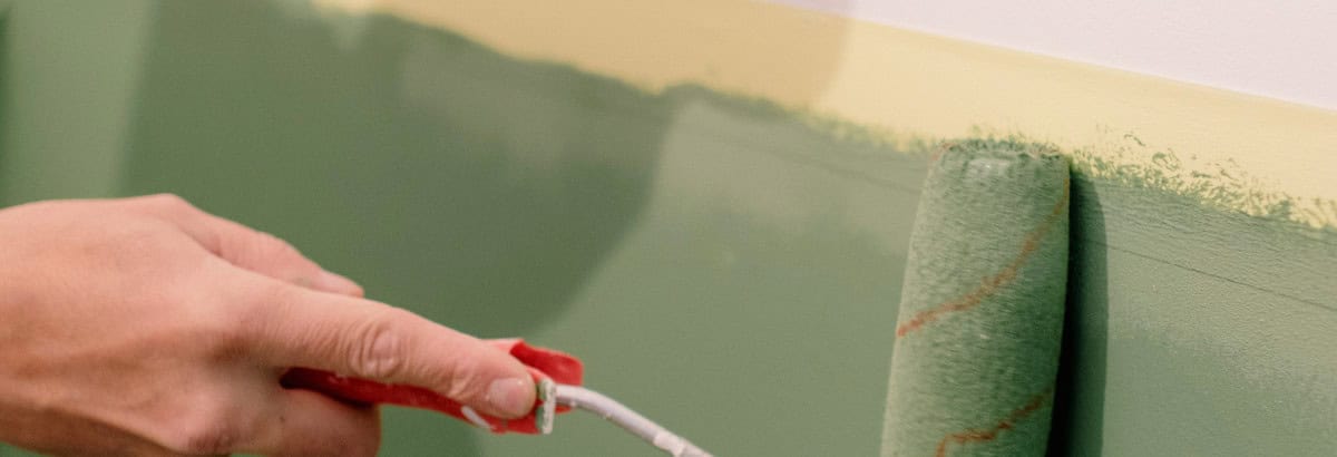 Un rouleau applique de la peinture verte sur un mur blanc, illustration des allégations environnementales visées par la directive EmpCo