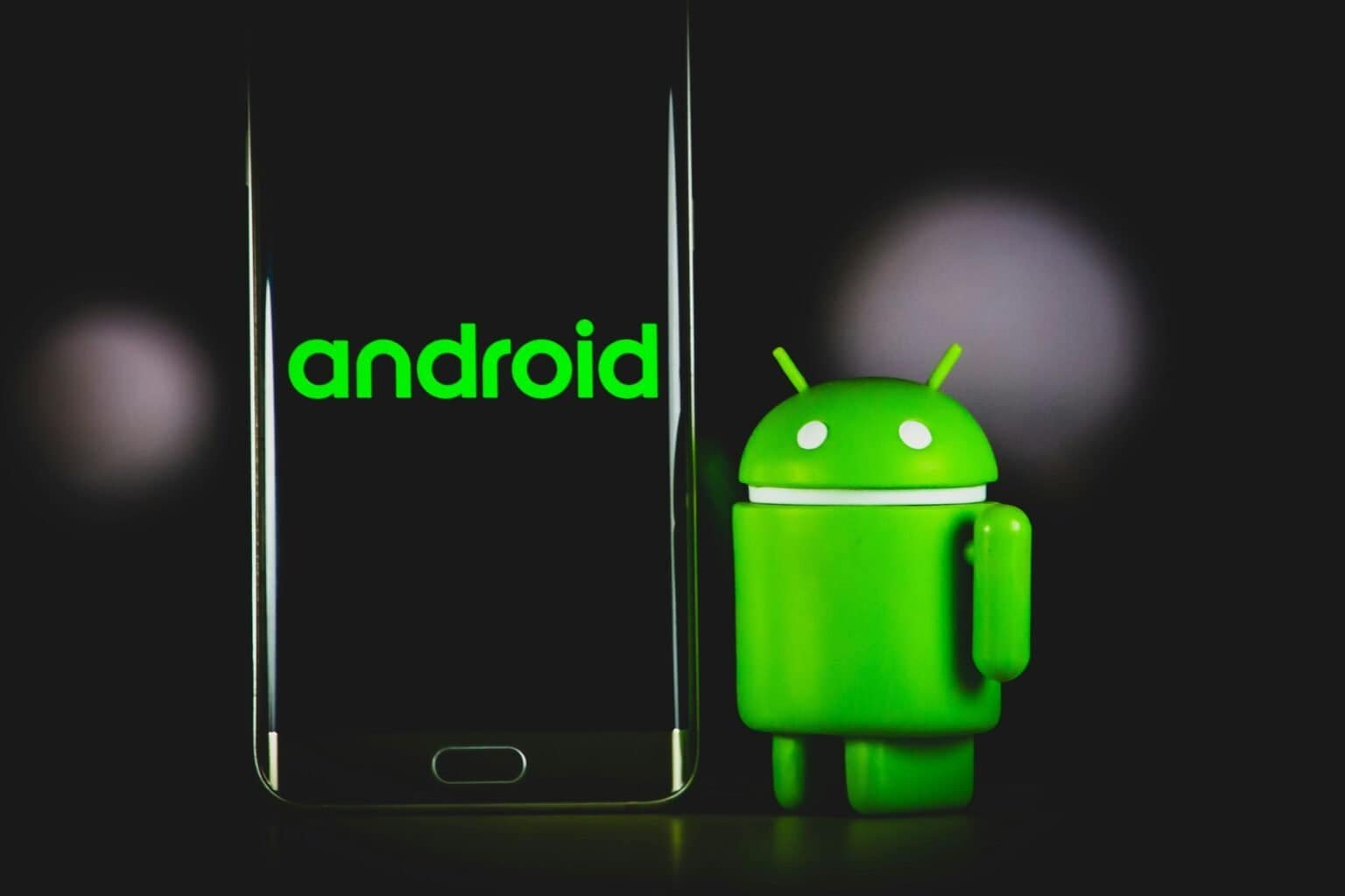 Android robot mascot and the Android logo on a smartphone screen.