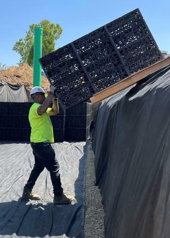 Underground stormwater detention system installation showing modular geocellular crates assembled below grade on a commercial construction site
