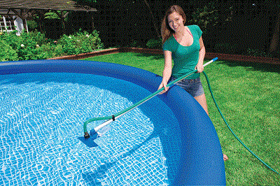 Vrouw maakt zwembad schoon in de tuin.