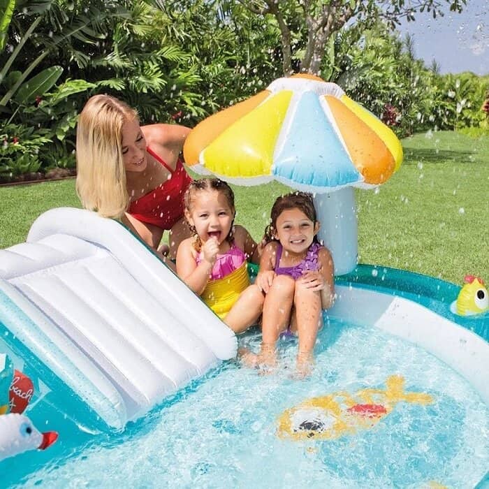 Kinderen spelen in opblaasbaar zwembad met glijbaan.