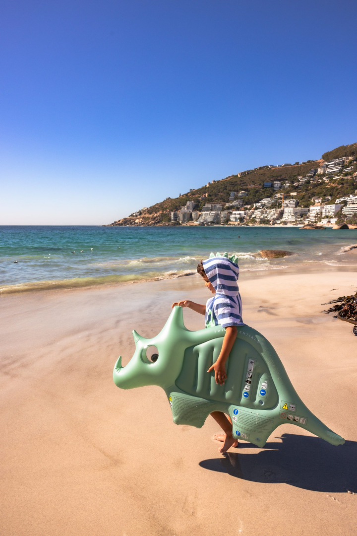 Kind met dinosaurus floatie op strand