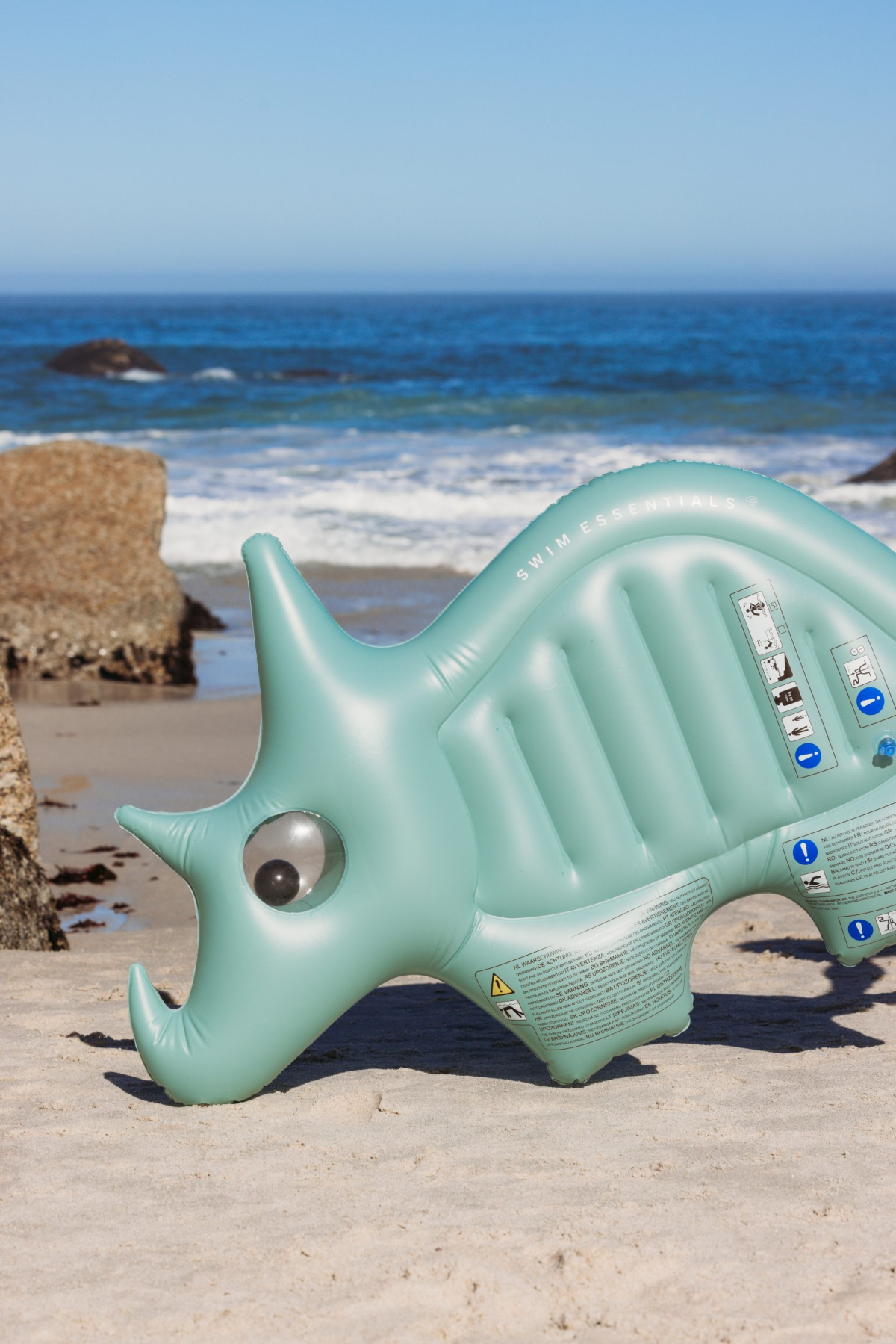 Oplegbare dinosaurus bij de zee op het strand.