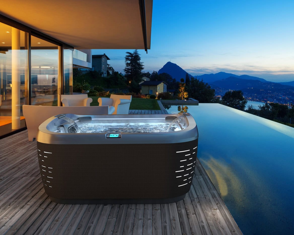 Bubbelbad op terras met uitzicht op bergen bij zonsondergang.