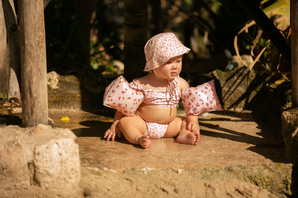 Baby in zwempak en hoedje buiten