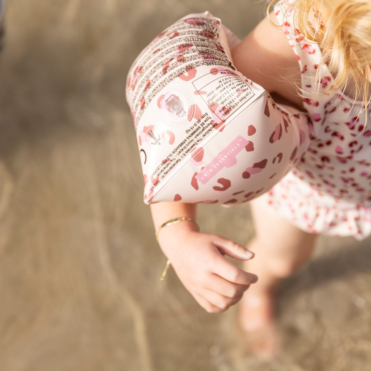 Kind met zwemvleugels loopt op strand