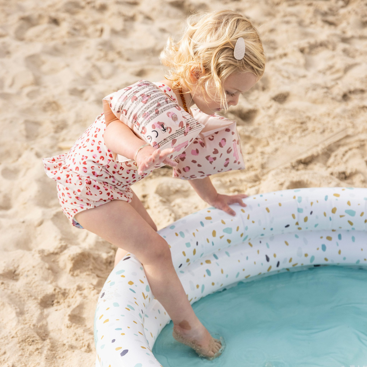 Kind speelt in opblaaszwembad op het strand.