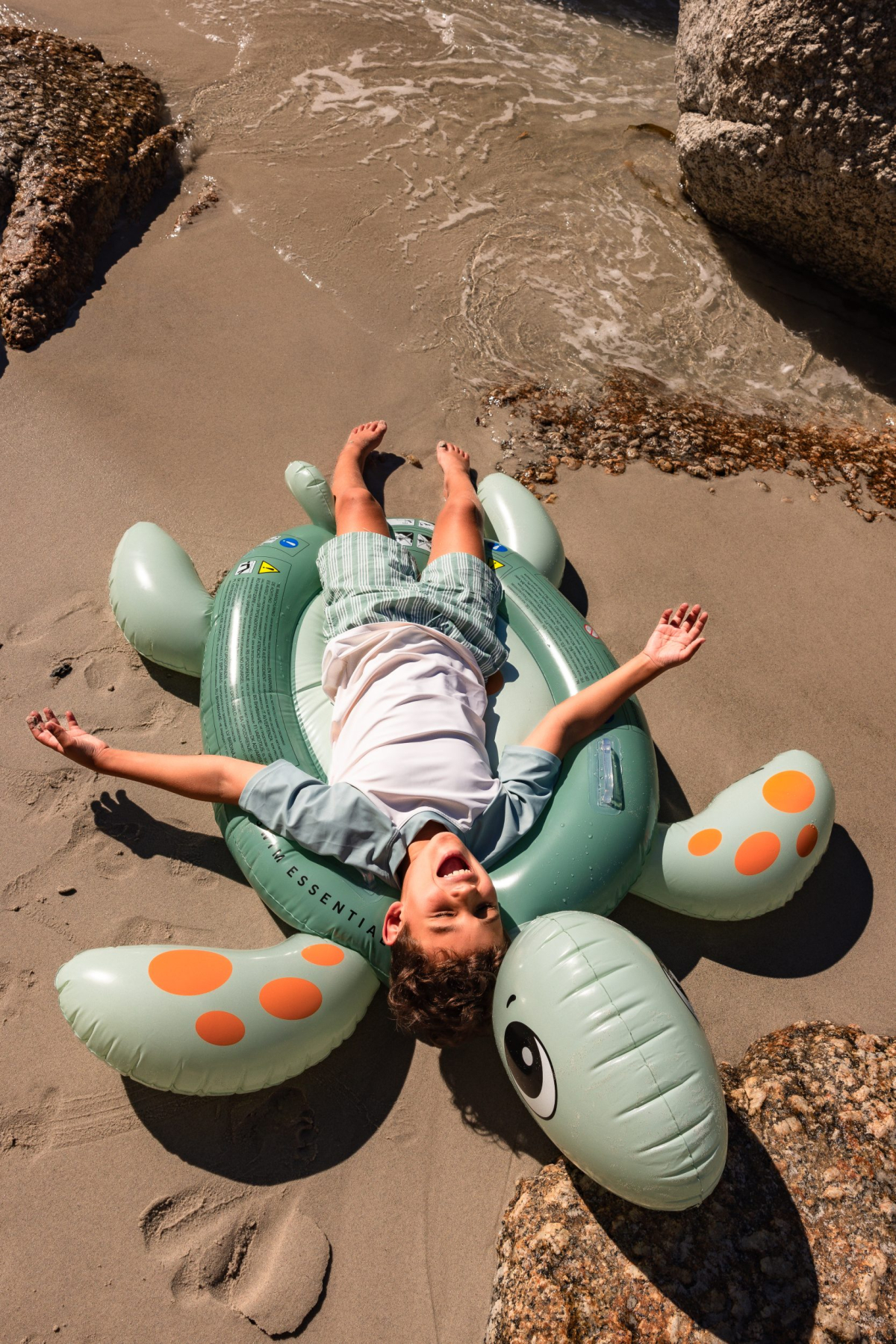 Kind op opblaasdier op het strand