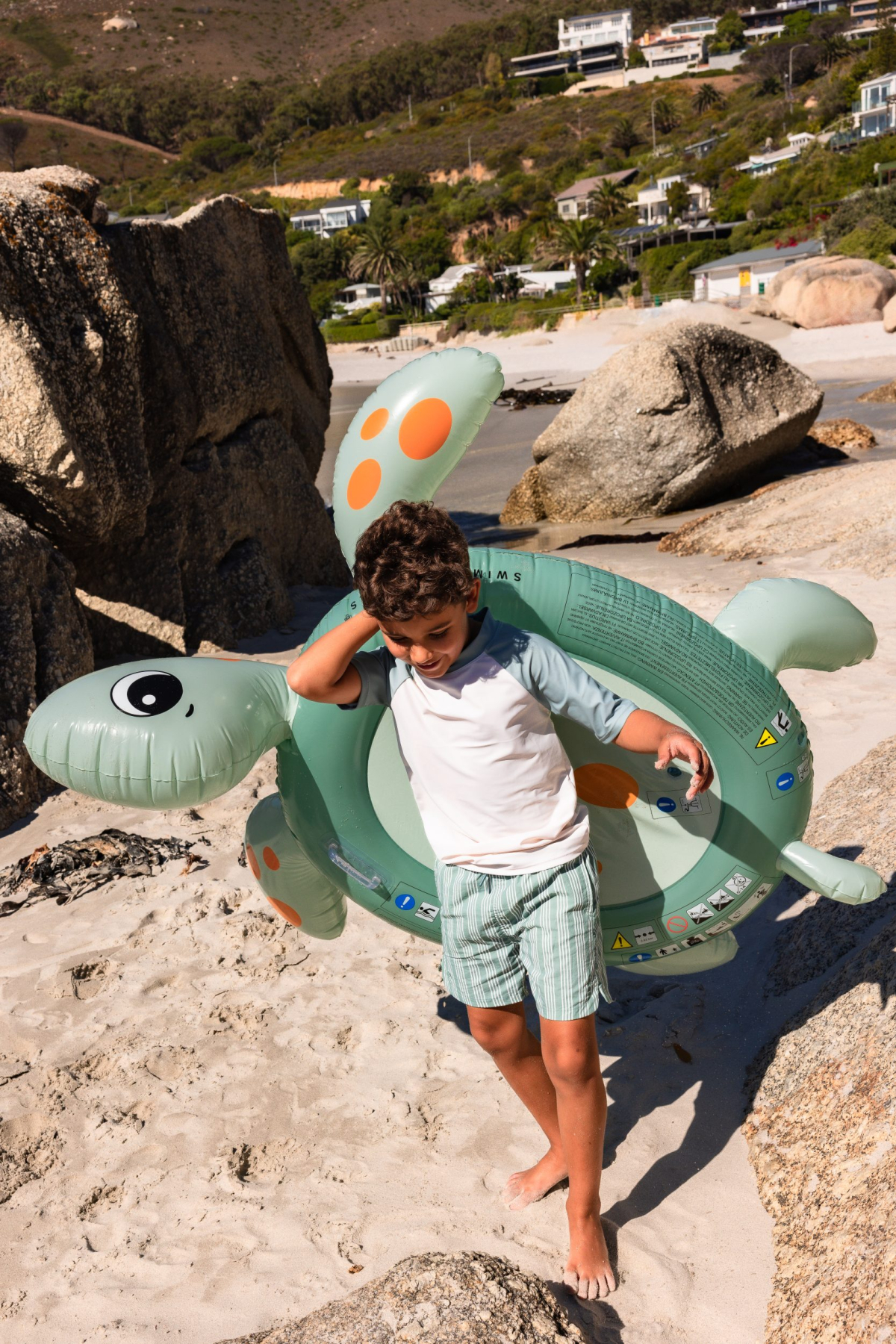 Jongen met opblaasbare schildpad op het strand