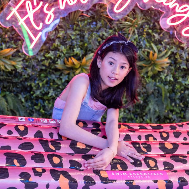 Meisje op roze opblaasmat met panterprint.