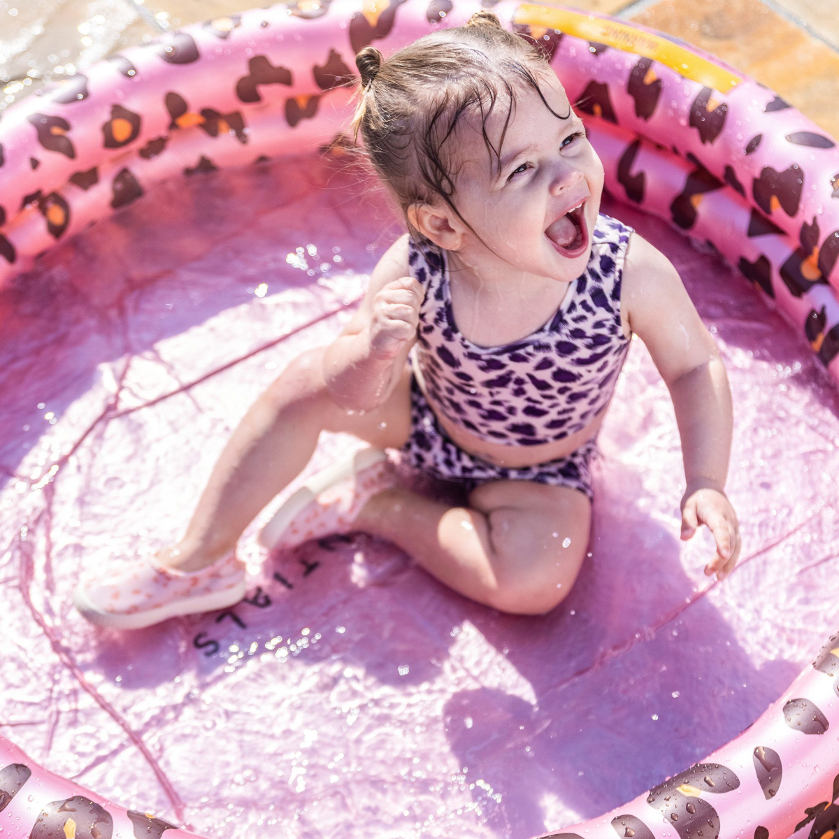 Blij kind in roze kinderzwembad