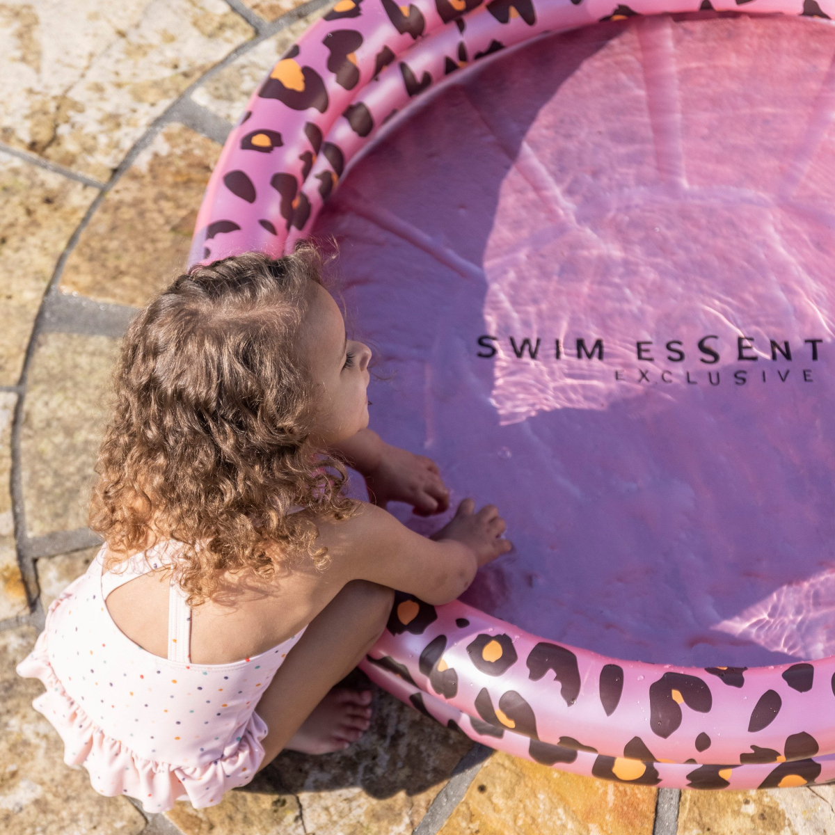 Kind in roze zwemband, speelt met water.
