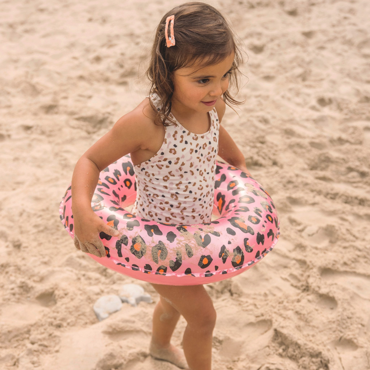 Kind met zwemband op zandstrand.