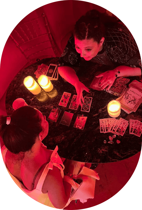 Vidente leyendo cartas de tarot en una sala con iluminación tenue y velas aromáticas.