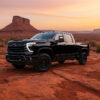 Stainless steel truck cap on black pickup truck in desert landscape at sunset.