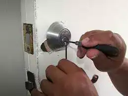 Locksmith locksmith installing or repairing door lock with screwdriver, professional locksmith services, home security, emergency lockout assistance, Fort Lauderdale.