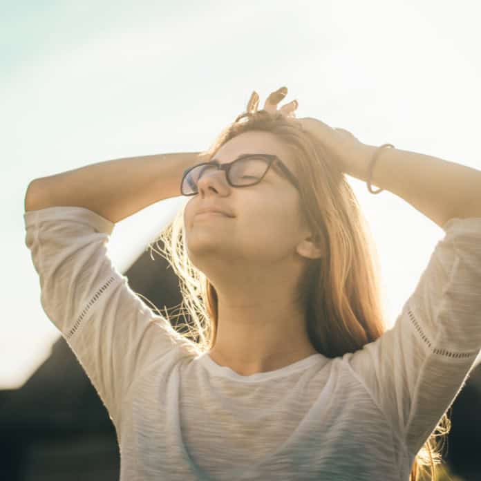 Relaxed young woman enjoying the sunlight with eyes closed, representing the calming and transformative benefits of hypnotherapy at Ashgrove Health Clinic Higham Ferrers.