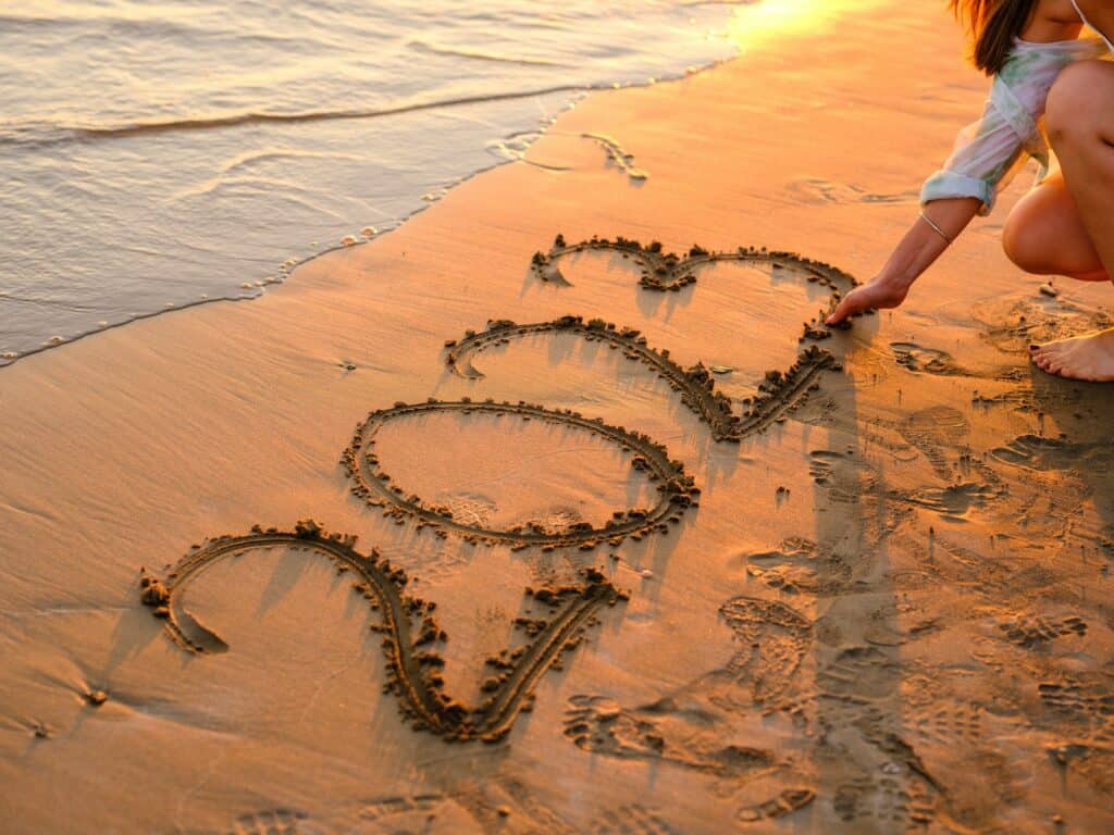 a person drawing a heart in the sand