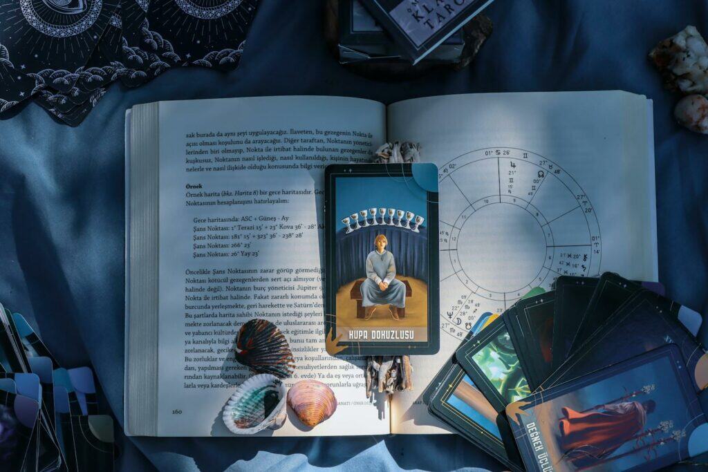 Horoscope Chart, An artistic flat lay of tarot cards and astrology on a book with seashells, featuring Kupa Dokuzlusu card.