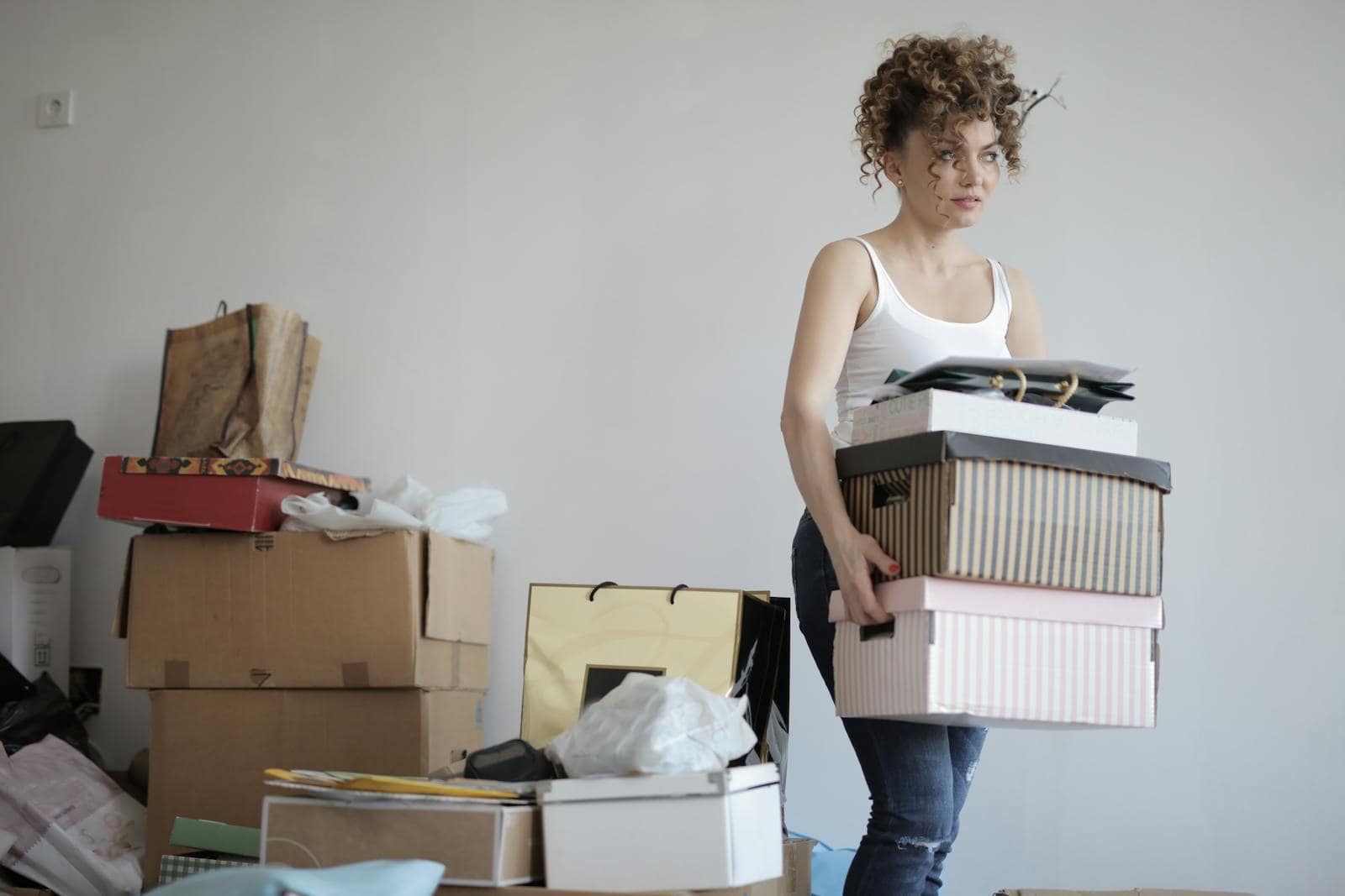 Astrological Houses, A young woman carrying boxes during a move into a new apartment, surrounded by packed belongings.