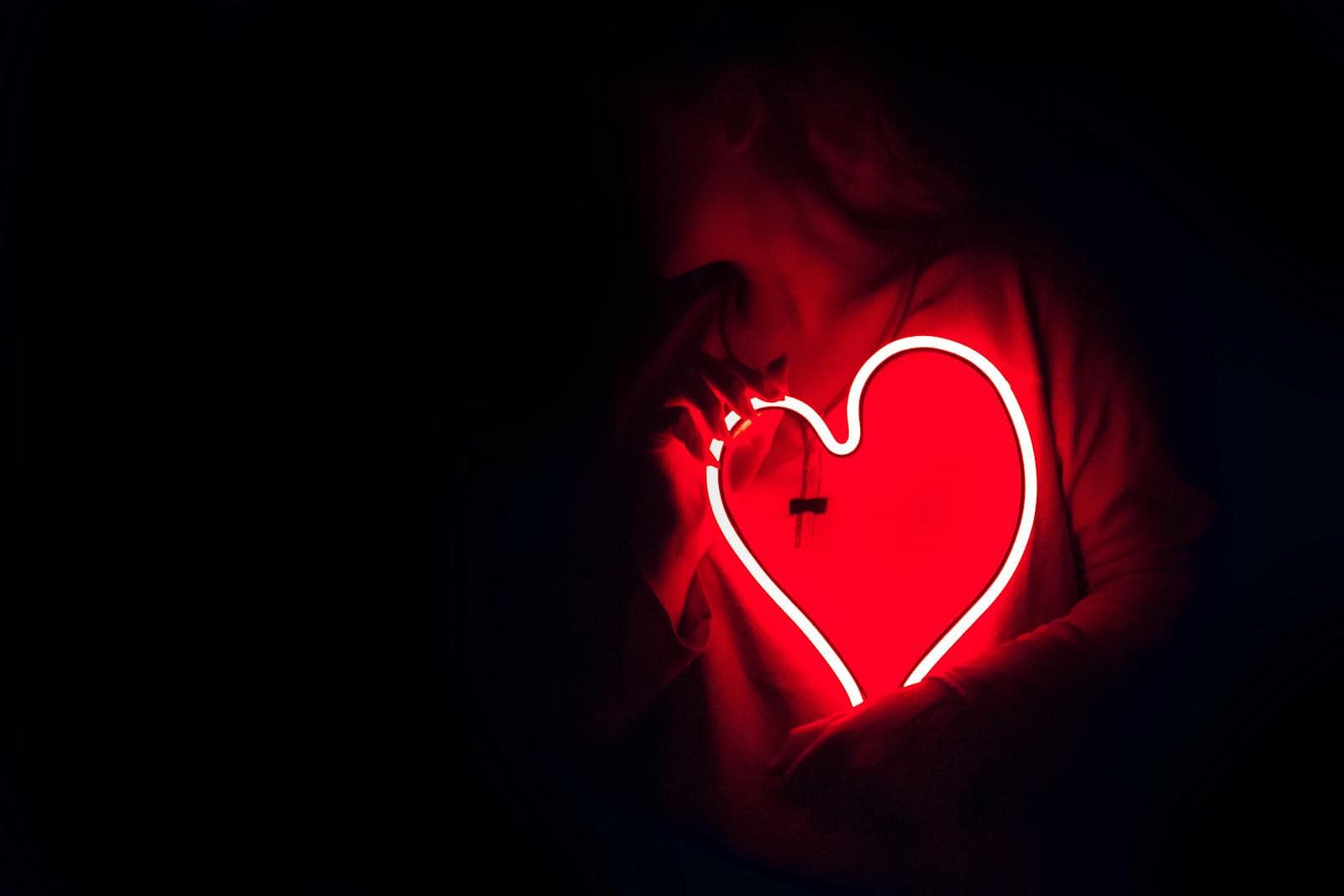 Horoscope Love Compatibility: Find Your Perfect Match, Silhouette of a person with a glowing red neon heart in the dark, symbolizing love.