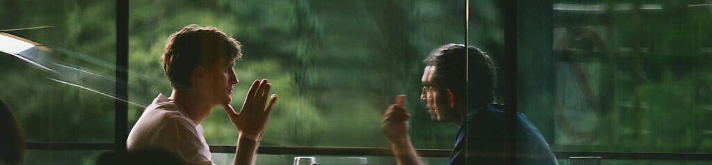Two people talking at a table in a restaurant.