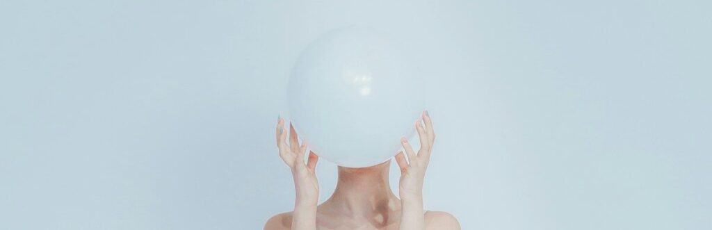 Woman holding a white balloon in front of her face.