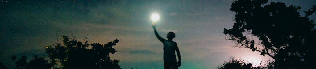 man in black tank top standing near tree under starry night