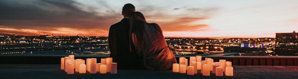 couple sitting on the field facing the city