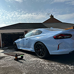 Blue sports car parked outside a garage.
