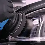 Car headlight being polished with a buffer tool