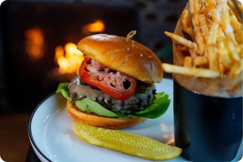 Juicy cheeseburger with lettuce, tomato, and pickles served with crispy fries at Attwood's Kitchen &.
