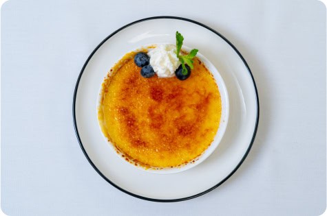 Creamy crème brûlée with caramelized sugar topping and fresh berries.