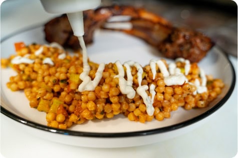 Delicious side dish with mustard sauce drizzled on top, served alongside grilled meat.