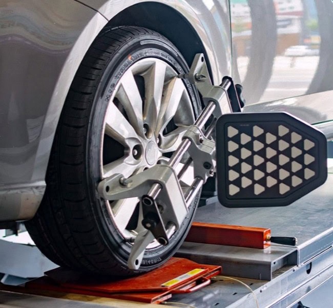 Car wheel on alignment rack with measurement device at an auto service shop.