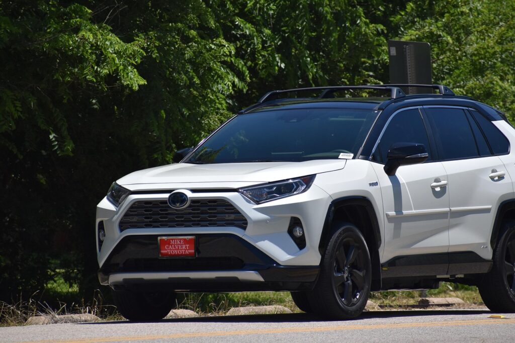 Toyota RAV4 Hybrid bílé SUV jedoucí na silnici v přírodě – spolehlivé auto žebříček 2026