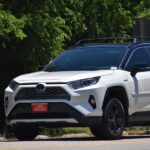 Toyota RAV4 Hybrid bílé SUV jedoucí na silnici v přírodě – spolehlivé auto žebříček 2026