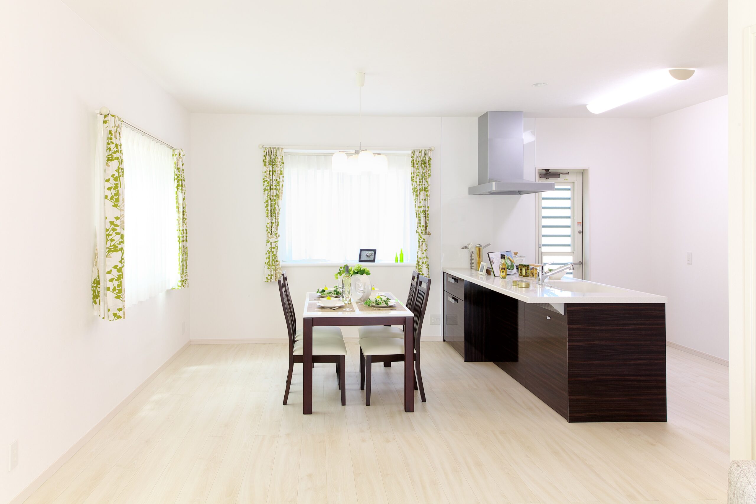 A clean, minimalist smart kitchen design in white with wood accents and pops of greenery