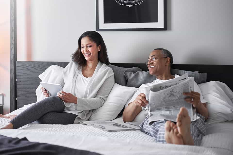 Relaxed couple enjoying breakfast in bed in a modern bedroom.