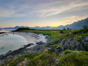 Kajakker og teltlejr ved kysten i Lofoten under solnedgang – naturskøn kajakoplevelse med roligt vand og fjeldlandskab