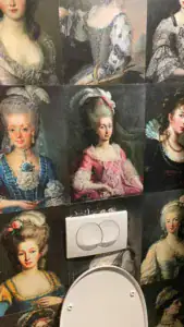 Væg dekoreret med klassiske portrætmalerier på toilettet på KEX Hostel