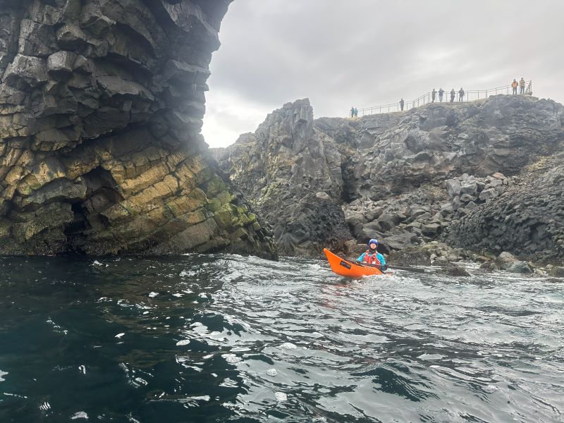Orange kajak ligger ved klipper