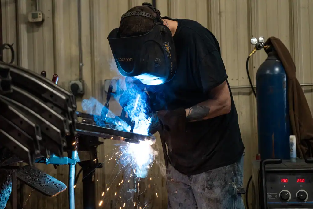 Skilled welder performing powder welding in industrial setting.