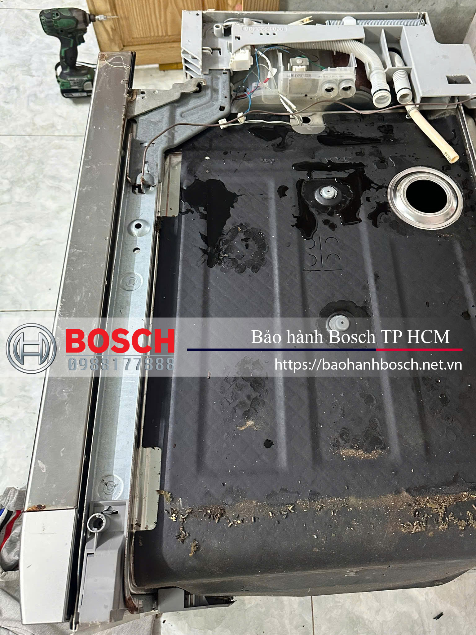 Đầu máy giặt Bosch bị mở ra để kiểm tra hoặc sửa chữa, với các linh kiện bên trong và phần khung máy. Hình ảnh thể hiện quá trình bảo hành hoặc bảo trì thiết bị Bosch tại TP HCM.