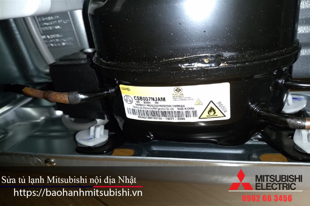 Refrigerant compressor for Mitsubishi electric refrigerator, with warning labels and copper piping, used in Mitsubishi appliances.
