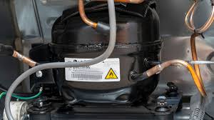 Compressor inside a Samsung refrigerator showing refrigeration system components and copper piping.