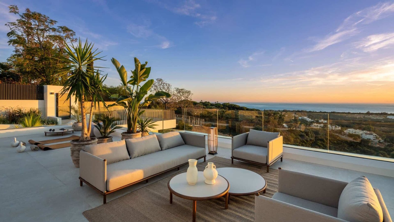 Modern outdoor lounge with ocean view at sunset, premium real estate setting.