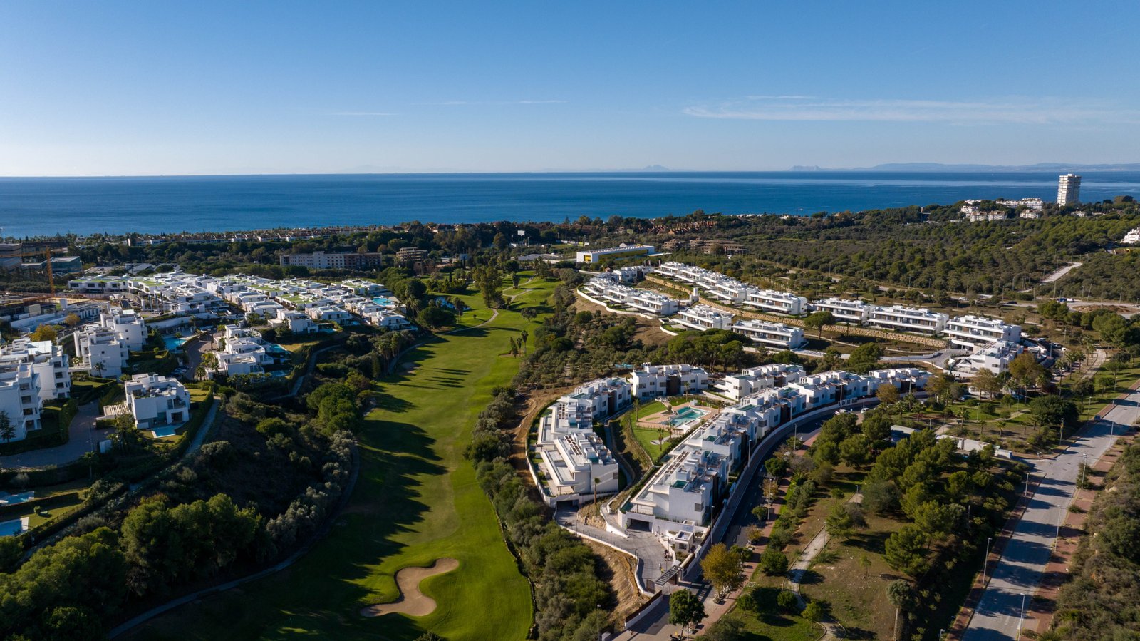 Aerial view of Santa Clara Golf Apartments Marbella with lush greenery and ocean in the background.
