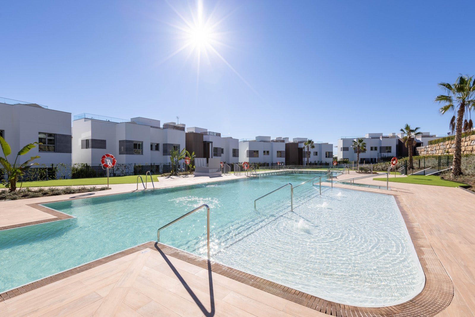 Pool area at Santa Clara Golf Apartments Marbella with modern residences and lush landscaping.