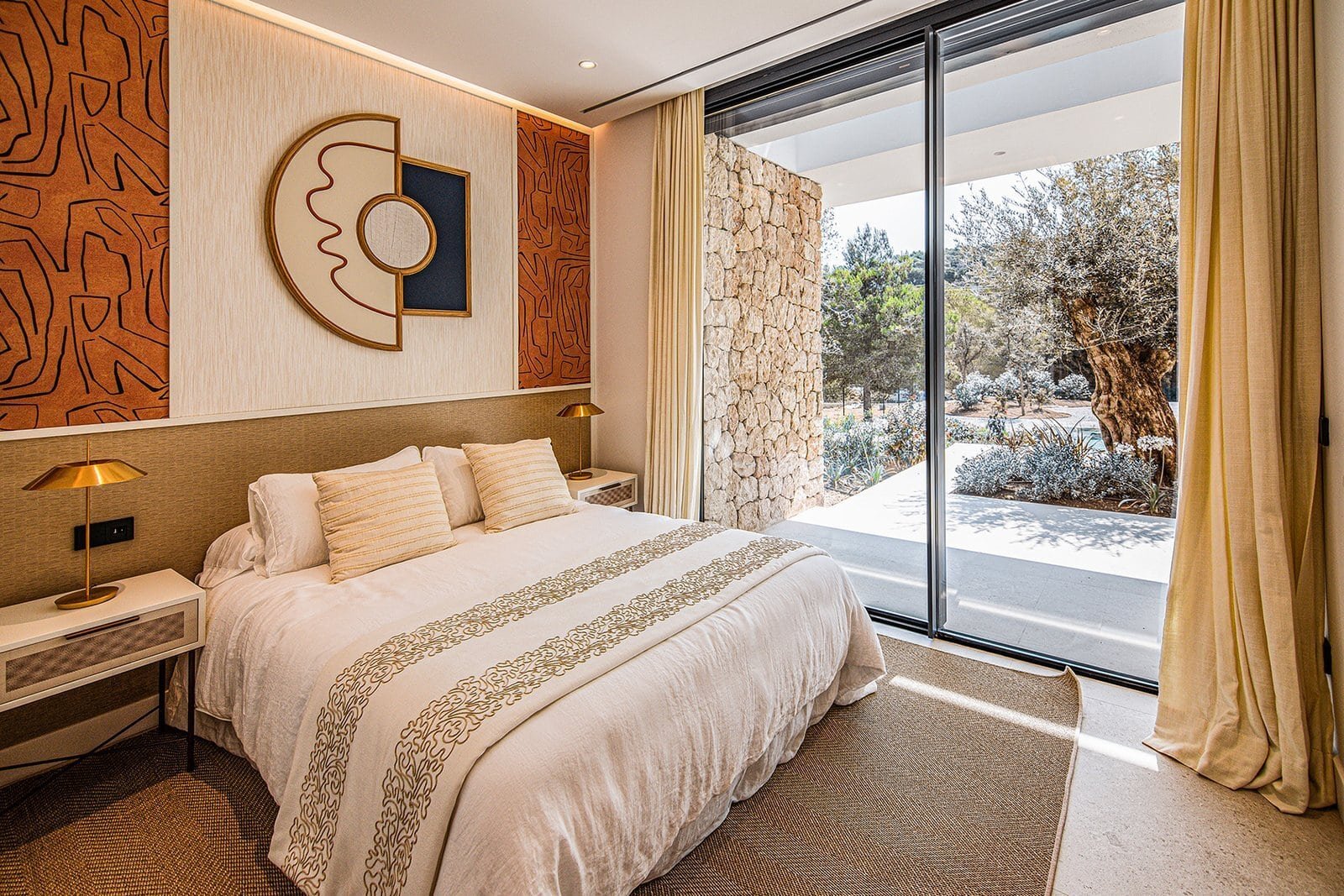 Luxury villa bedroom with modern decor and large glass doors overlooking lush golf course scenery.